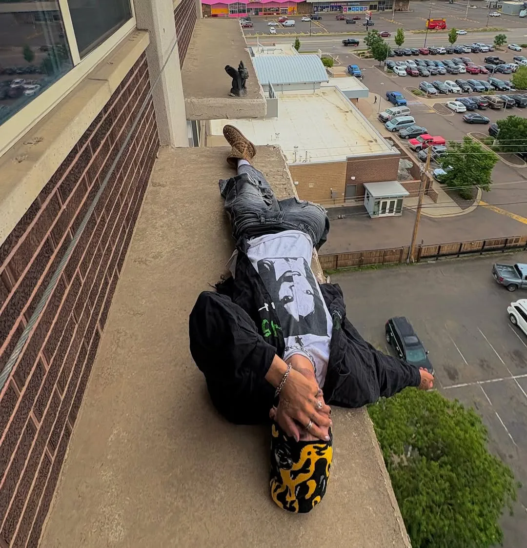 Skater lying flat across a rooftop ledge above a city carpark