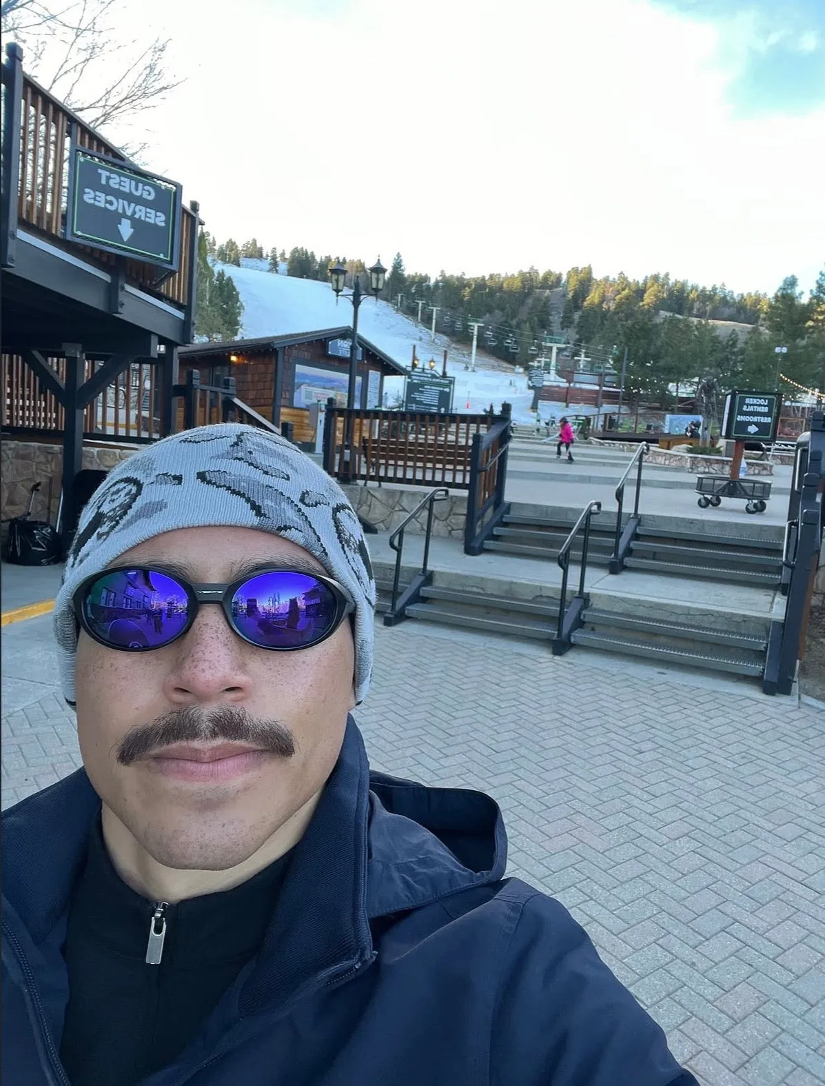 Selfie in mirrored shades and a patterned Two Frogs beanie at a ski-resort base